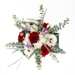 Through a florist's lens in the heart of Waterloo, this bouquet captures both tradition and urban artistry. Long-stemmed, sumptuous red roses anchor the design, paired beautifully with sleek white gerbera daisies whose prominent mahogany centers add a classic, confident flair. A scattering of lilac and lavender lisianthus, some gently unfurling, infuses the arrangement with modern softness and a sense of quiet anticipation. Downy clusters of white filler flowers create subtle contrasts and visual interest, recalling the shifting clouds above Waterloo Bridge. The aromatic eucalyptus leaves, which glisten with silvery hues, thread through the display, catching the light like city park foliage after rainshower. At the base, dark glossy leaves wrap the bouquet neatly, elegantly framing the stems immersed in water within the transparent vase. Perfect for sending love or encouragement to someone near The Old Vic or welcoming guests to a flat near York Road, this arrangement champions the quality and artistry of Waterloo's local florists.